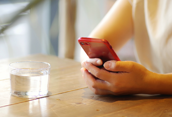 スマホを抱え不安そうな女性の手元。