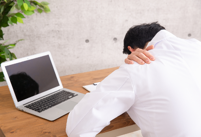 パソコンの前で項垂れる医師。