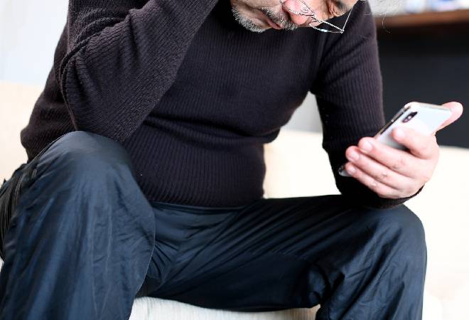 スマホを手に項垂れる男性。